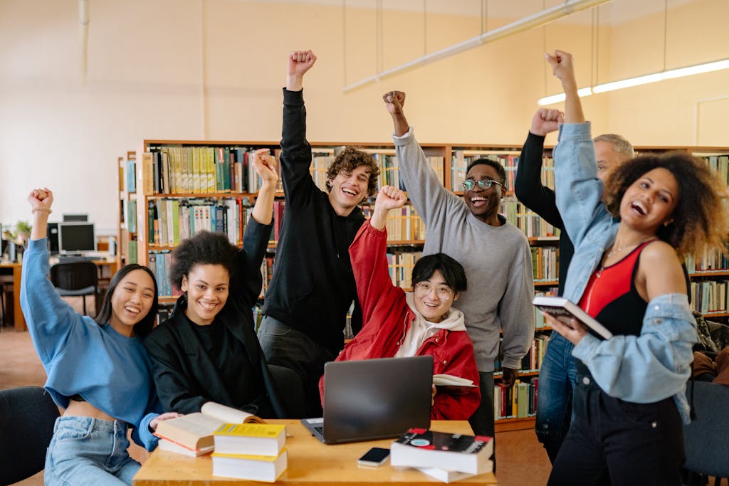 Group of People Smiling and Standing Near Brown Wooden Table Raising Hands